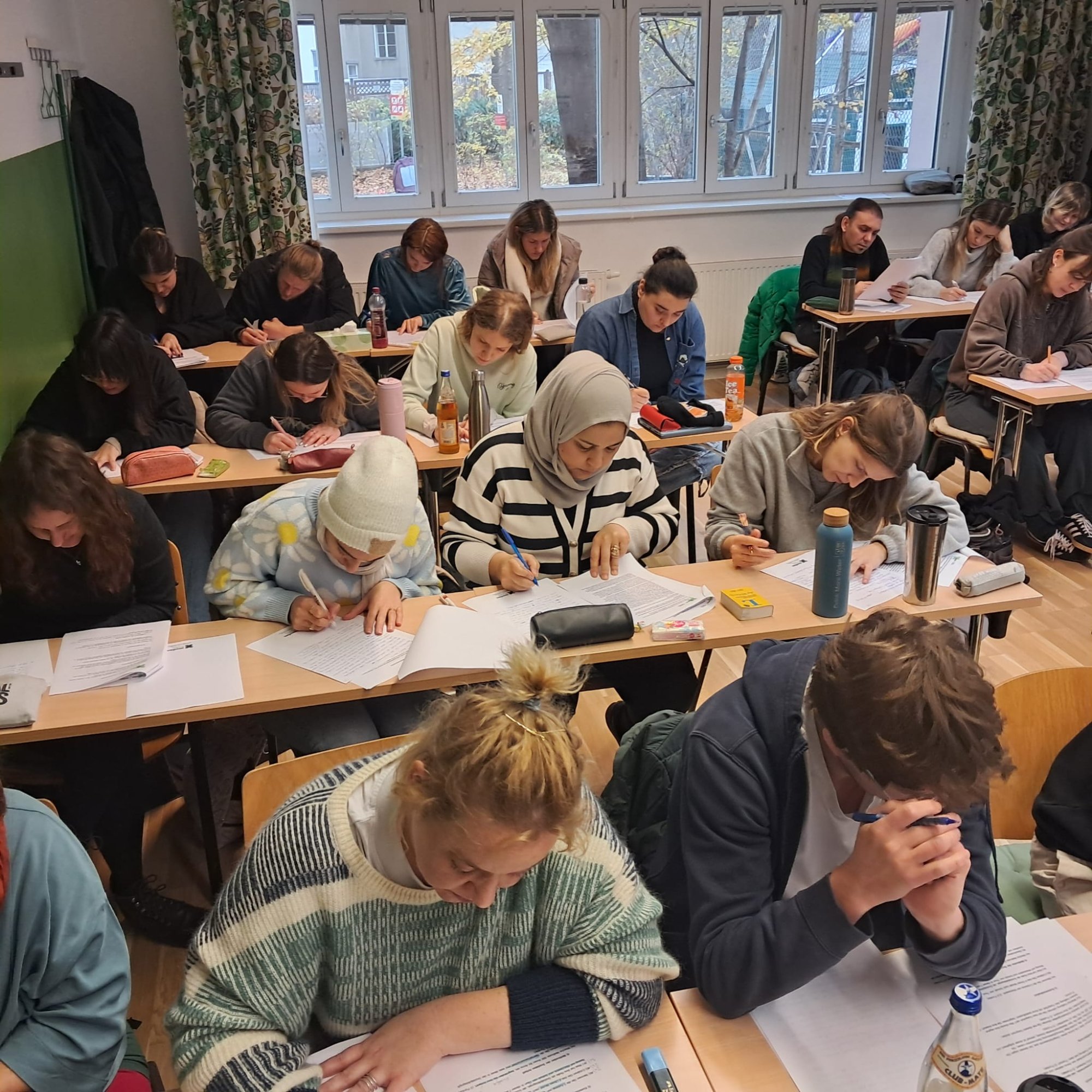 Studierende schreiben konzentriert im Klassenraum