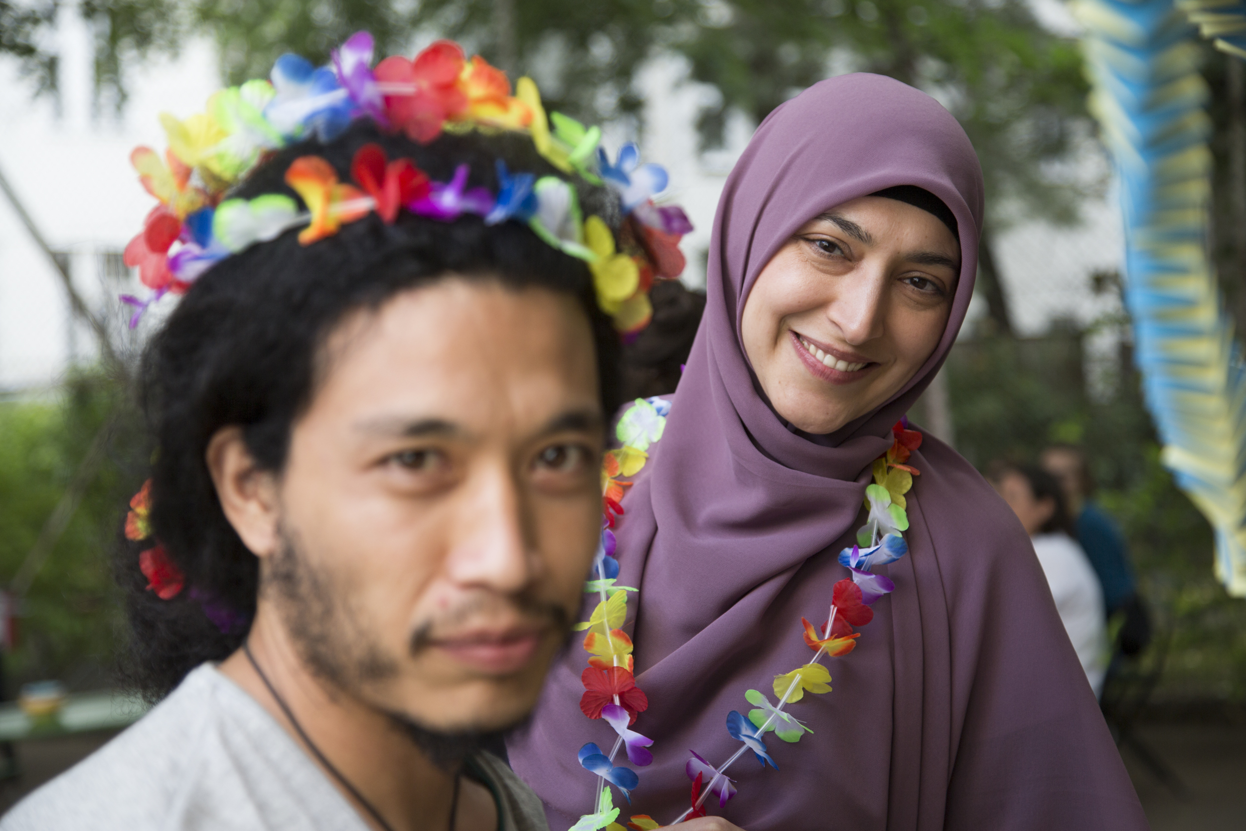 Zwei Studierende mit bunten Blumenkränzen bei einem Fest im Innenhof