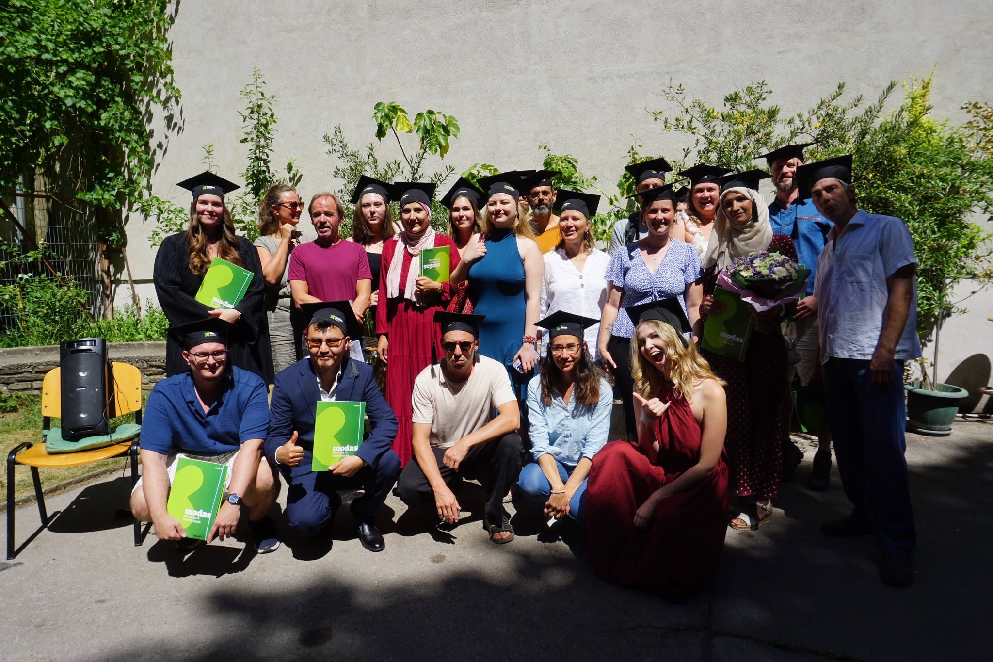 Absolvent*innen von modas mit Diplommappen und Hüten im Innenhof
